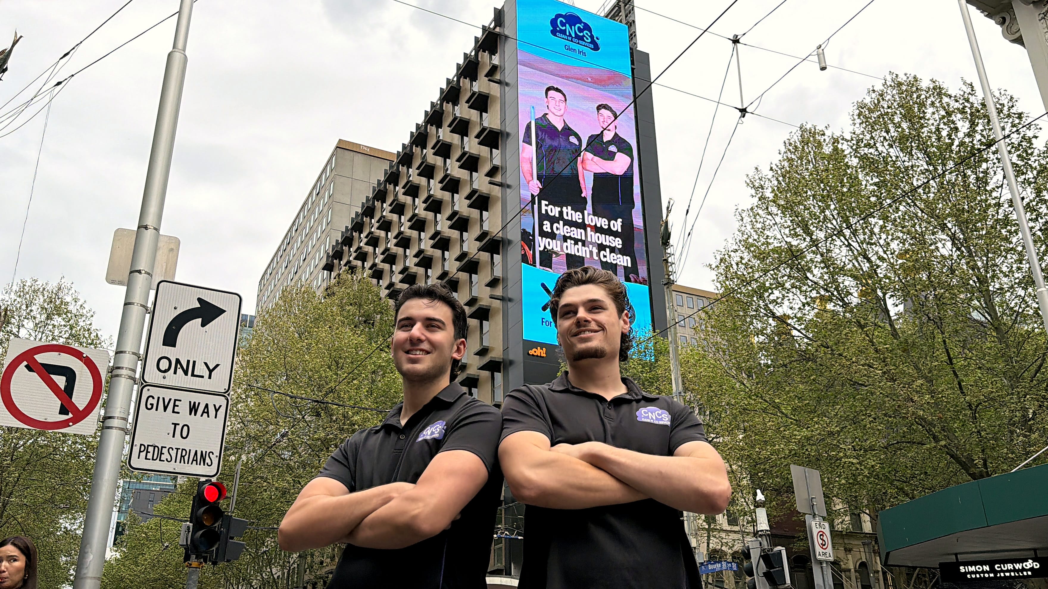 Liam and Andrew, the founders of Clean N' Co, in front of their billboard on Bourke Street, Melbourne